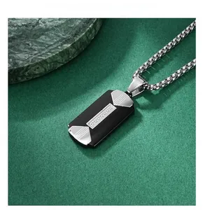 Close-up of a two-tone black and silver rectangular military style pendant on green marble