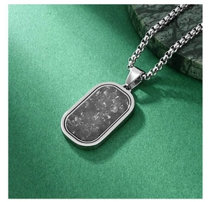Detailed close-up of a men's silver rectangular military pendant with carbon fiber inlay