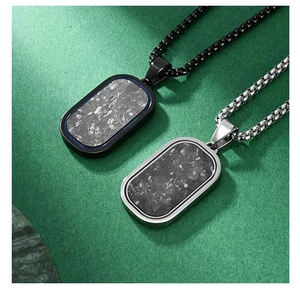 Close-up of black and silver stainless steel pendants with textured carbon fiber inlay
