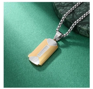 Detail of two-tone stainless steel pendant with gold finish and silver box chain