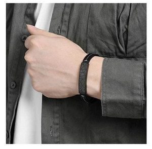 Detailed view of black leather bracelet featuring cracked geometric patterns and white stitching