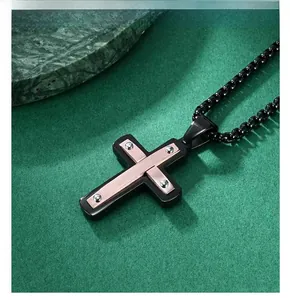 Détail d'un pendentif croix en acier bicolore avec insert or rose et chaîne maille vénitienne
