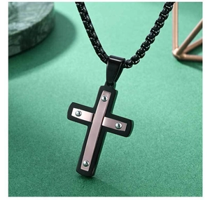 Vue macro du pendentif croix en acier avec accents or rose et rivets argentés
