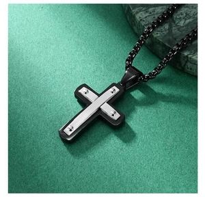 Détail du pendentif croix en acier inoxydable bicolore avec rivets argentés sur base noire