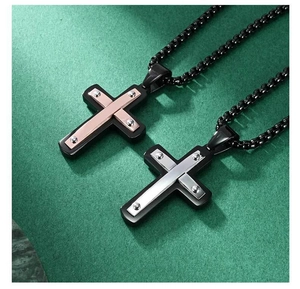 Détail du pendentif croix en acier bicolore avec rivets sur une chaîne à billes noire