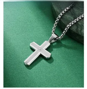 Macro shot of brushed stainless steel cross pendant with a single zircon inlay