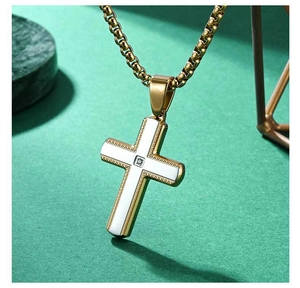 Detail of a gold-plated cross pendant with white inlay and a small center diamond