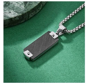 Detail of hip hop dog tag pendant featuring black brushed texture and silver screw accents
