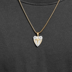 Collana con ciondolo a scudo meccanico con croce d'oro e texture argento su maglione