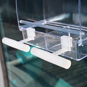 Detail view showing transparent acrylic bird feeder with non-slip white perch rods
