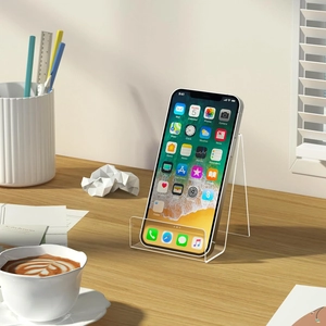 Detailed close-up of a transparent acrylic phone stand on a wooden desk with a smartphone