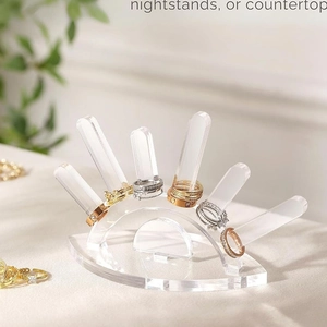 Close-up of minimalist clear acrylic 5-finger ring display stand on nightstand