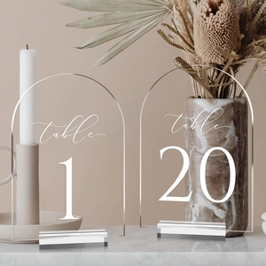 Makro-Detail eleganter bogenförmiger Acryl-Tischnummern für Hochzeiten mit Ständern
