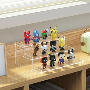 Three-tier clear acrylic display stand with figures on a natural wood surface