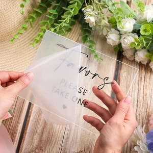 Clear acrylic wedding favor sign being peeled from film on rustic wooden floor