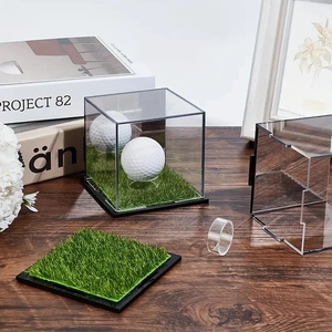 Detail of acrylic golf ball display case with green turf base and clear holder on desk