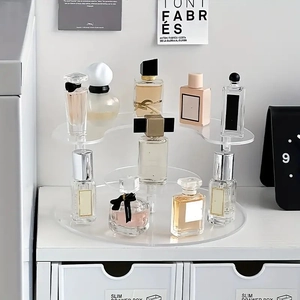 Multi-tier clear acrylic display stand for perfume and collectibles on a white desk