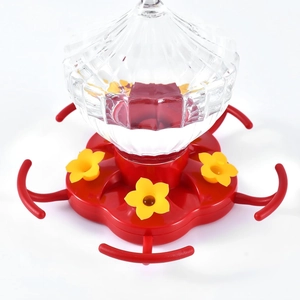 Pumpkin-shaped hummingbird feeder with ribbed glass bottle and red flower feeding ports