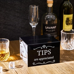 Boîte à pourboires en acrylique noir avec texte sur un comptoir de bar en bois