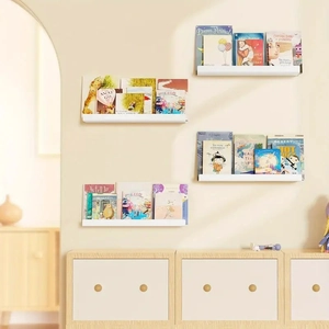 Close-up of four white floating wall shelves displaying children books in a nursery