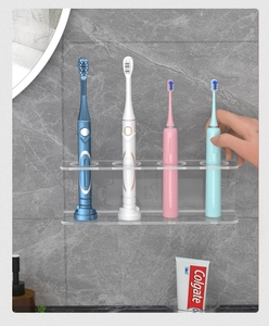 Macro shot of wall-mounted clear acrylic holder for four electric toothbrushes
