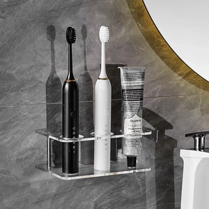 Wall-mounted transparent acrylic toothbrush holder with 3 holes on gray marble wall