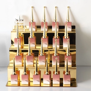 Golden tiered acrylic stand displaying gradient pink lipstick tubes with pointed caps