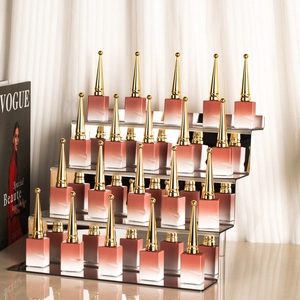 Golden acrylic tiered display stand showcasing elegant gradient lip gloss tubes