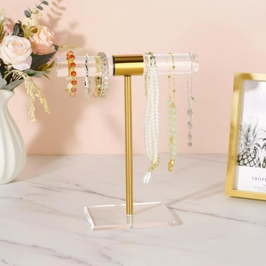 Macro view of T-bar jewelry stand with gold metal accents and clear acrylic base display