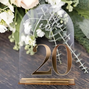 Close-up of arched acrylic table number with gold mirror base and floral background