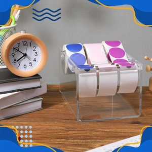 Clear acrylic label dispenser with three slots on a desk showing neat sticker storage