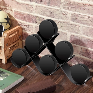 Black acrylic tiered display stand holding six hockey pucks on a dark wooden surface