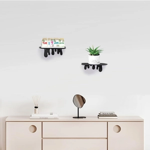 Detail view of two black fluid dripping design acrylic floating shelves on a white wall
