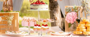 Outdoor setup of a 3-tier clear acrylic cupcake stand with fresh strawberry cakes