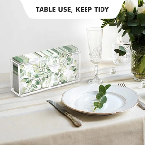 Modern acrylic napkin holder on a dining table with green leaf pattern guest towels