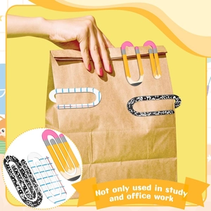 Macro view of creative oversized acrylic paper clips with pencil and marble designs on a kraft bag