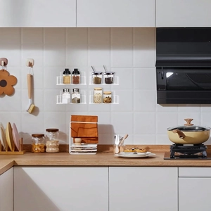Set of four clear acrylic wall-mounted spice racks holding glass jars in a kitchen