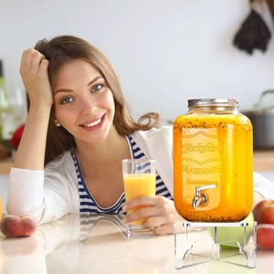 Clear acrylic drink dispenser stand shown in a bright kitchen with a glass beverage jar