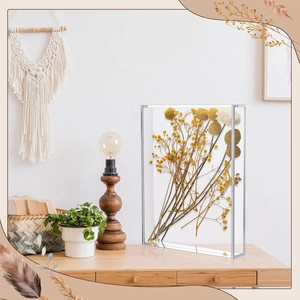 Detail of clear acrylic display box featuring preserved yellow flowers on a wooden desk