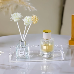 Clear wavy acrylic vanity tray for perfume and aromatherapy bottles on marble surface