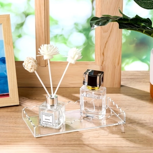 Modern wavy acrylic vanity tray with aromatherapy bottle and perfume on a desk