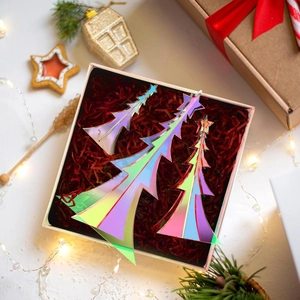 Flat-lay detail of three iridescent acrylic Christmas trees in a festive gift box setup