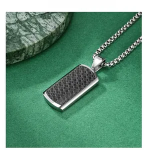 Detail of rectangular titanium steel pendant with black woven texture and silver border