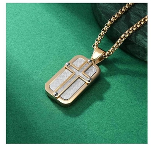 Macro detail of a dual-tone cross pendant with gold box chain on a marble background