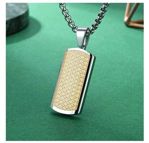 Macro detail of rectangle titanium steel pendant featuring golden woven texture and polished frame