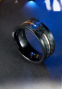 Détail macro d'une bague homme en acier inoxydable avec fibre de carbone et or rose