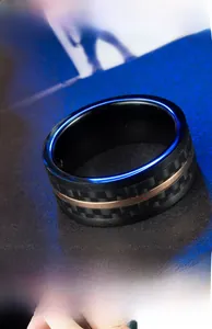 Gros plan sur une bague homme en acier noir avec fibre de carbone et ligne d'or rose