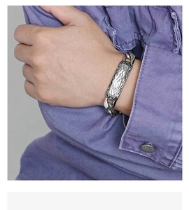 Detail of silver men's stainless steel curb chain bracelet with hammered texture plaque