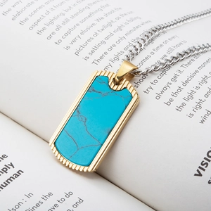 Men's rectangular gold pendant with turquoise stone on silver Cuban chain over a book