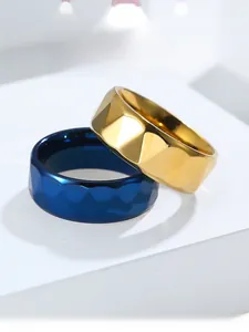 Close-up of gold and navy blue faceted tungsten-style steel rings with polished finish